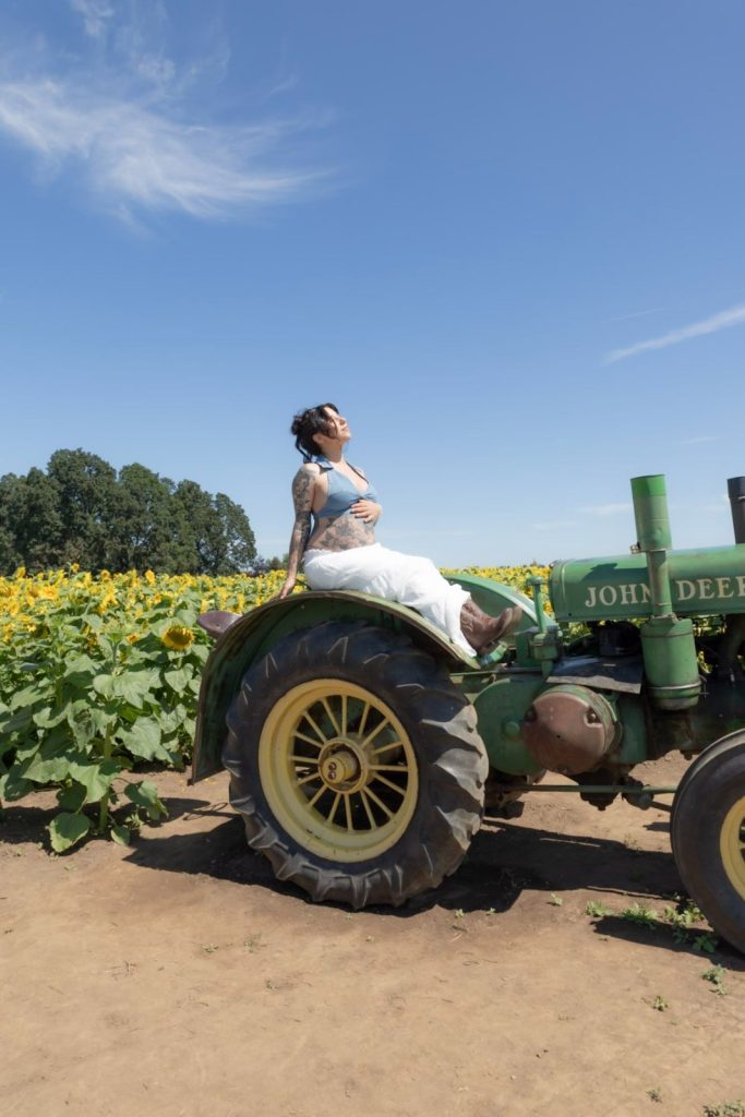 woman riding 1958 John Deere 530 vintage tractor through sunflower field