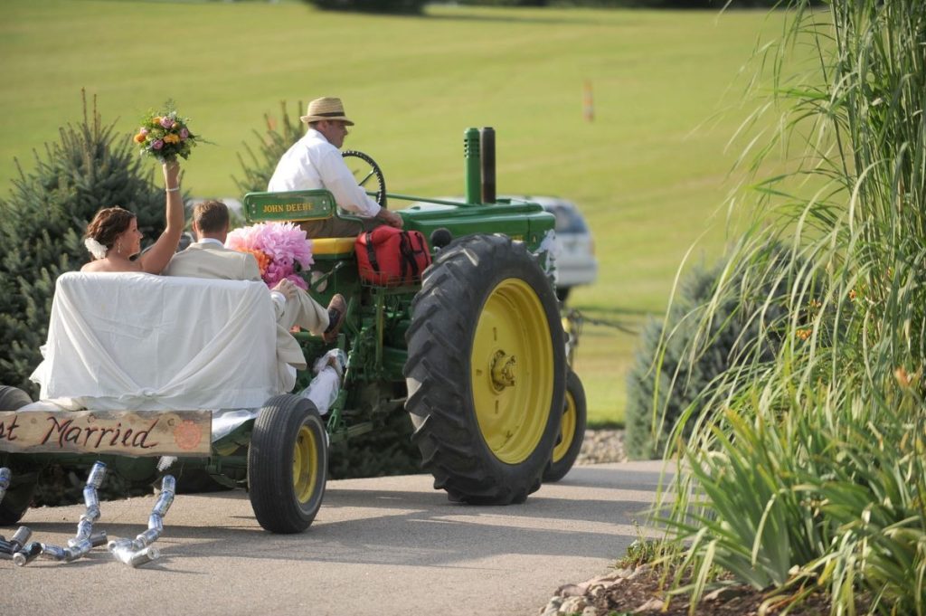 John Deere 530 vintage tractor pulling Just Married newlyweds in wagon down country road